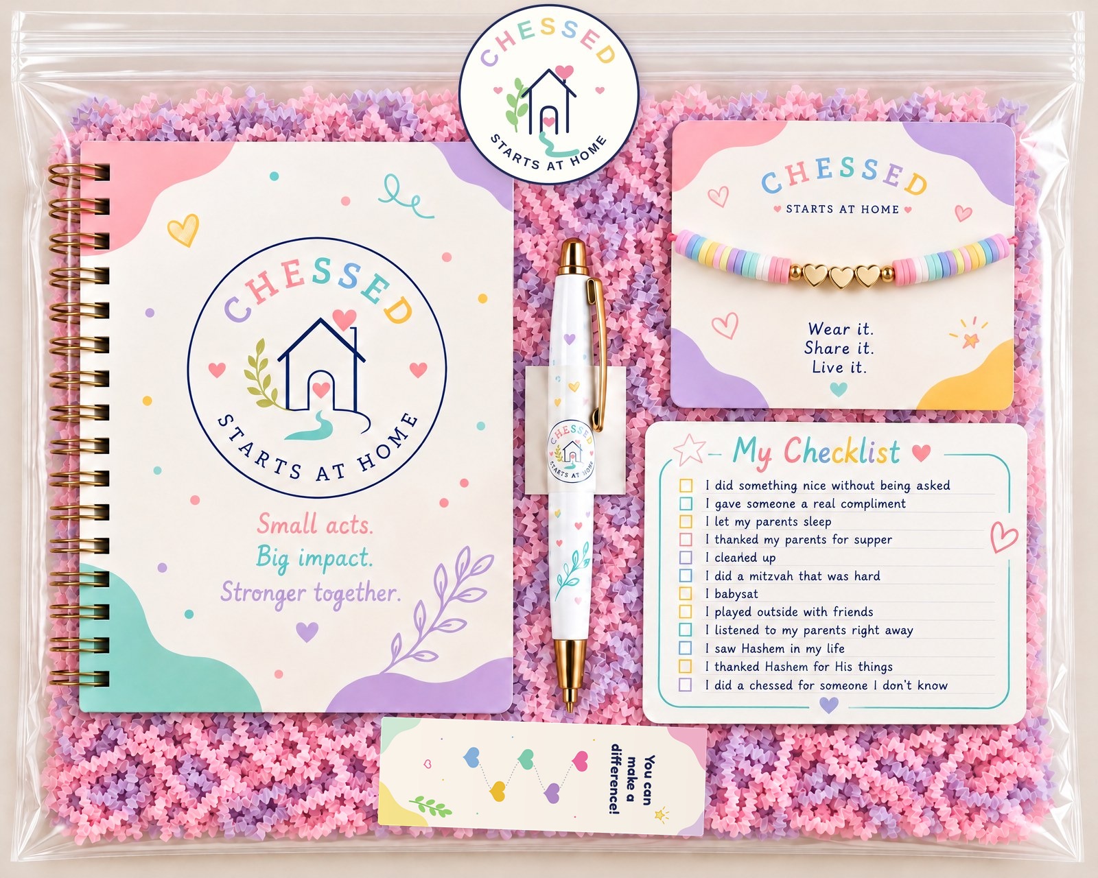 The Chessed Starts at Home kit: spiral journal, logo sticker, pen, beaded bracelet, My Checklist card and a bookmark of girls holding hands